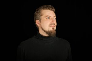 Cute bearded man, half-profile portrait, black background